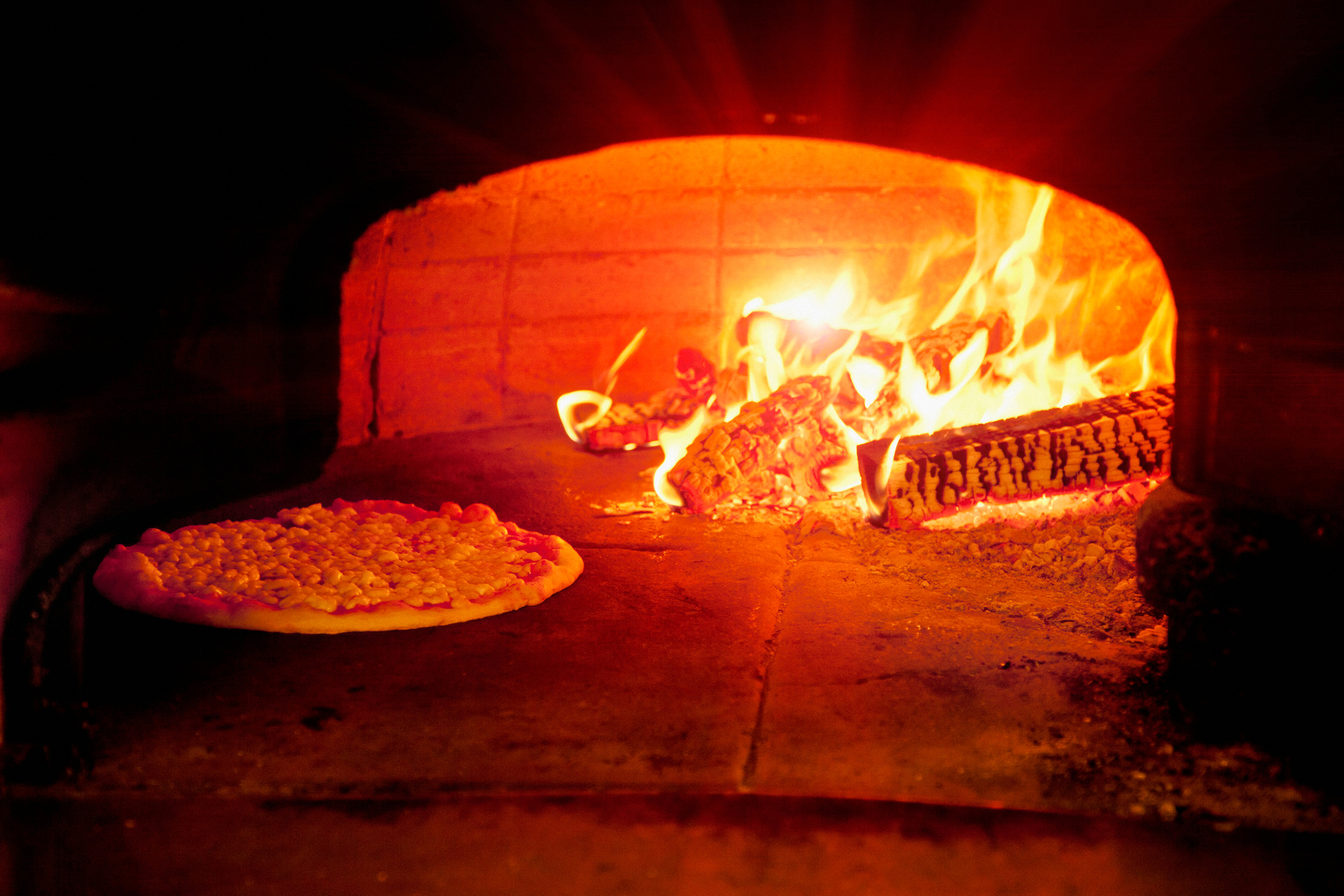 "Pizza baking in wood burning oven